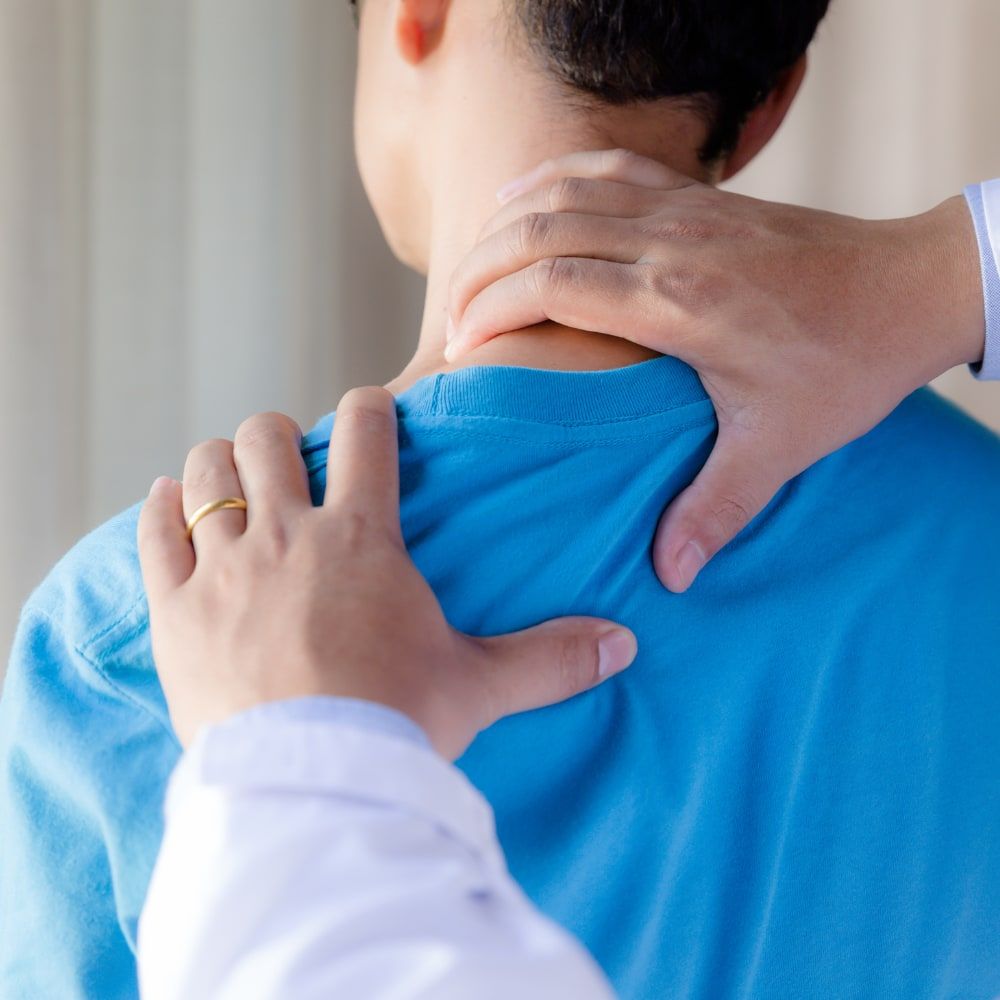 Mains d’un physiothérapeute évaluant la nuque et l’épaule d’une patiente
